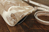 Cowhide Crossbody Saddle Bag side view features a unique pattern of shades of cream, khaki, and chocolate. Shown in color [Cowhide A] and features adjustable strap and strap keeper..