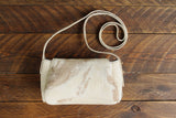 Cowhide Crossbody Saddle Bag back view features a unique pattern of shades of cream, khaki, and chocolate. Shown in color [Cowhide B].