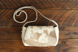 Cowhide Crossbody Saddle Bag front view features a unique pattern of shades of cream, khaki, and chocolate. Shown in color [Cowhide B].