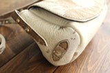Cowhide Crossbody Saddle Bag side view features the adjustable strap and strap keeper. Shown in color [Cowhide B].