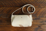 Cowhide Crossbody Saddle Bag back view features a unique pattern of shades of cream, khaki, and chocolate. Shown in color [Cowhide C].
