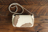 Cowhide Crossbody Saddle Bag front view features a unique pattern of shades of cream, khaki, and chocolate. Shown in color [Cowhide C].