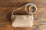 Cowhide Crossbody Saddle Bag back view features a unique pattern of shades of cream, khaki, and chocolate. Shown in color [Cowhide D].