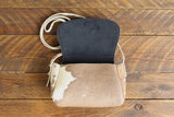 Cowhide Crossbody Saddle Bag open view features a unique pattern of shades of cream, khaki, and chocolate and Dark Denim Blue suede interior lining. Shown in color [Cowhide D].