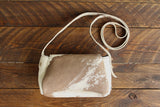 Cowhide Crossbody Saddle Bag back view features a unique pattern of shades of cream, khaki, and chocolate. Shown in color [Cowhide E].