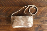 Cowhide Crossbody Saddle Bag back view features a unique pattern of shades of cream, khaki, and chocolate. Shown in color [Cowhide F].