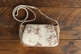 Cowhide Crossbody Saddle Bag front view features a unique pattern of shades of cream, khaki, and chocolate. Shown in color [Cowhide F].