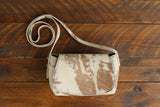 Cowhide Crossbody Saddle Bag front view features a unique pattern of shades of cream, khaki, and chocolate. Shown in color [Cowhide G].