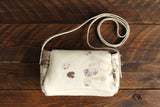 Cowhide Crossbody Saddle Bag back view features a unique pattern of shades of cream, khaki, and chocolate. Shown in color [Cowhide H].