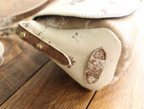 Cowhide Crossbody Saddle Bag side view features the adjustable strap and strap keeper. Shown in color [Cowhide H].