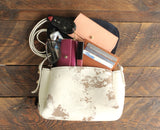 Cowhide crossbody shown with personal items in it.