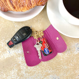 Fuchsia George Key Case open on table showing key and store loyalty cards inside.